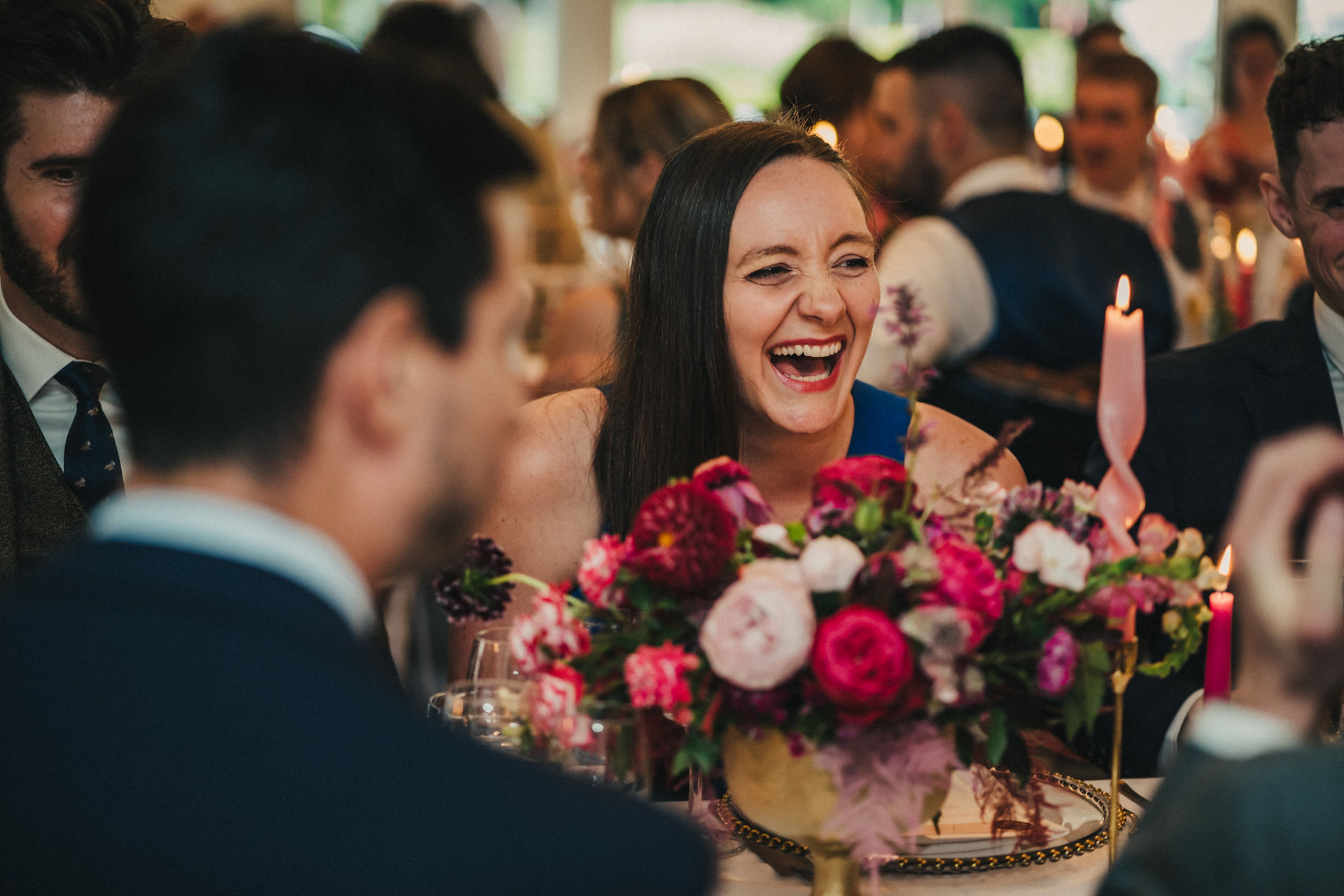 guest at a wedding laughing with a bowl of flowers by Jacqui O in the centre