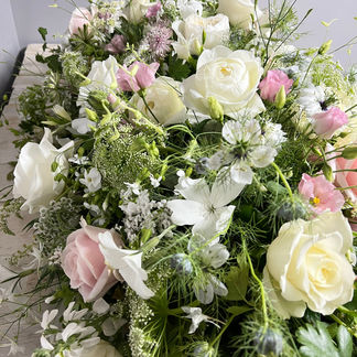 A casket tribute in pinks and white in a garden-esque display of gorgeous roses, delicate nigella and pretty ammi perfect for a garden lover made by Jacqui O of Nantwich, Cheshire