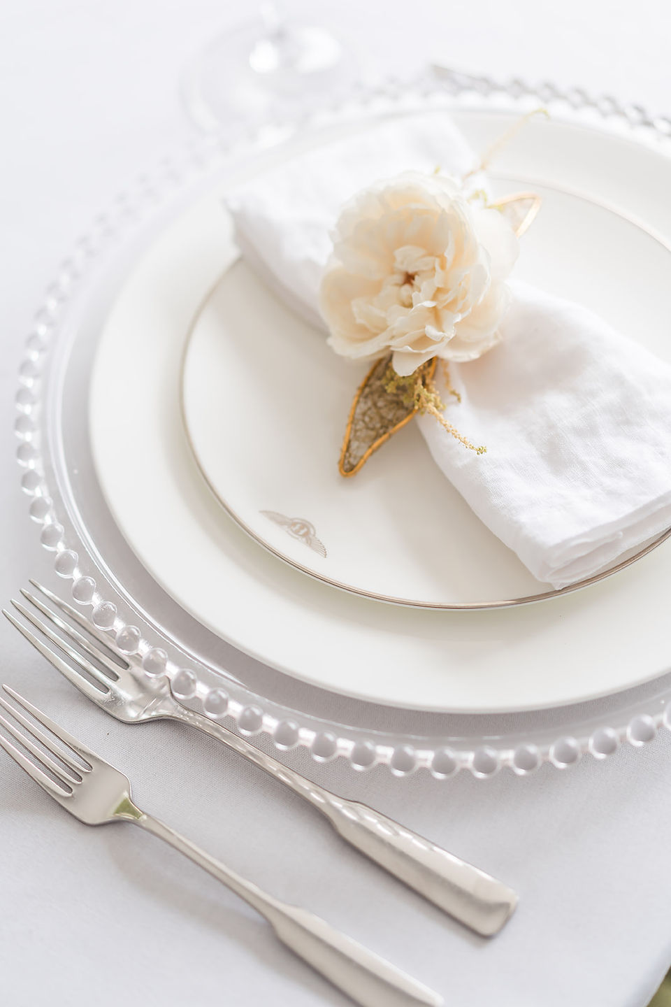 dinner plates with a nakin and a rose placed on a handmade gold holder by Jacqui O