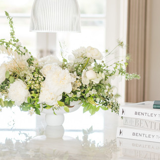 A spring bowl of flowers of peonies, fox gloves and spirea sitt on a marble table from bentely home