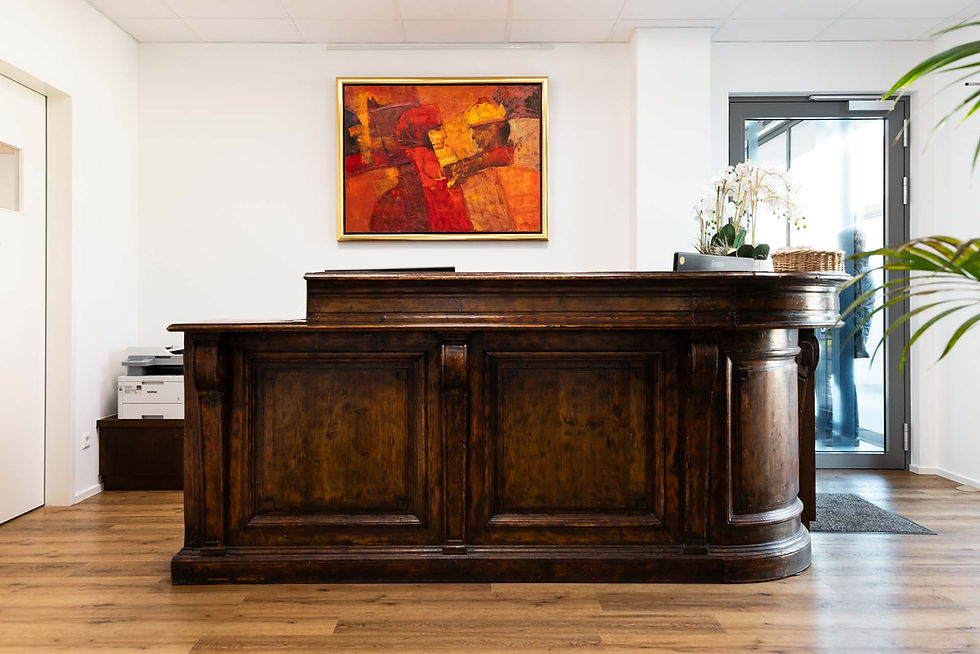Antiker Tresen aus Holz vor einer weißen Wand an der ein rotes Gemälde hängt