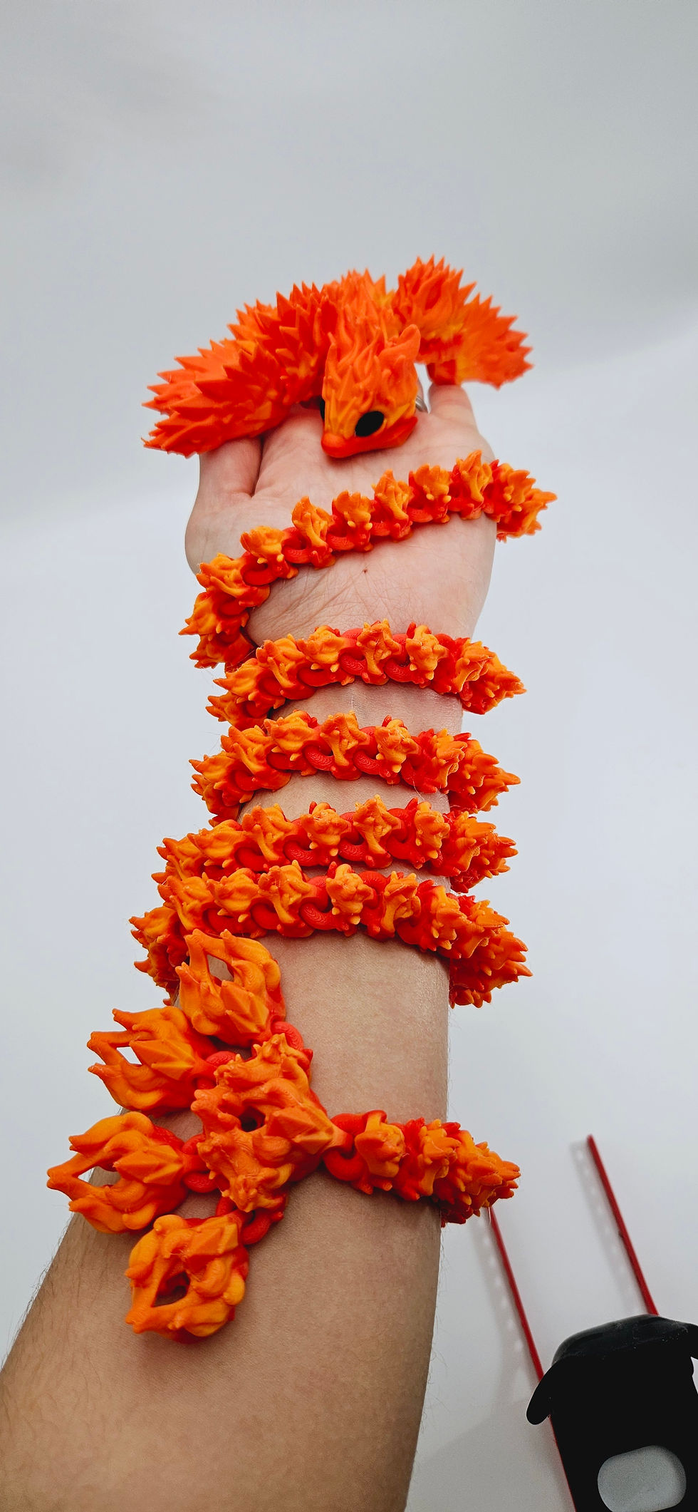 Thumbnail: Young girl holding a 3D printed long baby fire dragon showing its length