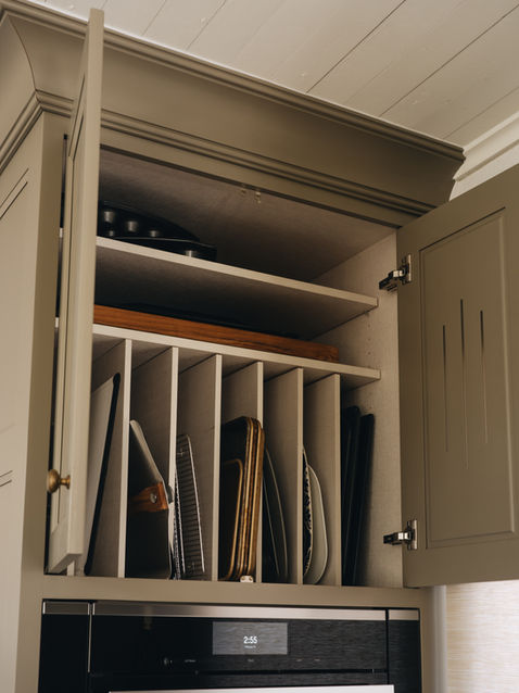 Light green cabinetry with cream interiors and a vertical pan divider for organized storage.