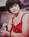 Woman in red polka-dot top holding sunglasses