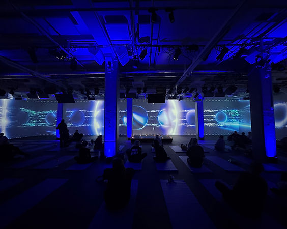 Participants doing pilates in an immersive audiovisual installation with large-scale blue projections