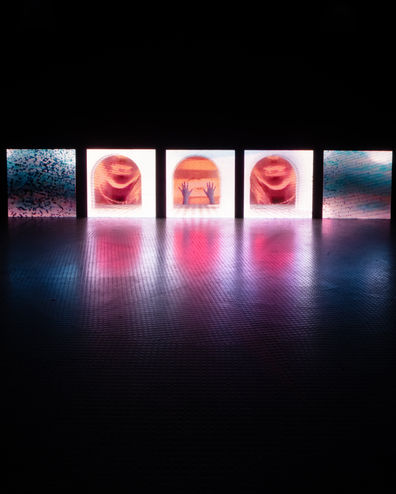 Wide view of immersive installation space with multiple LED screens displaying abstract digital visuals
