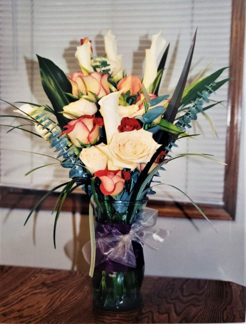 Simple Vase arrangement consisting of:
Full Dark Orange Roses
Variegated Full Coral Roses
Full Cream/Yellow Roses
Stripe Zebra Grass
Tropical Leaves
Cobalt Blue Stem Wrap