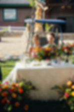 wedding couple at their sweetheart table with meadow floral arrangements in front