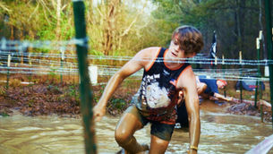 A lionhearts fitness athlete crawls through the mud at Spartan Atlanta