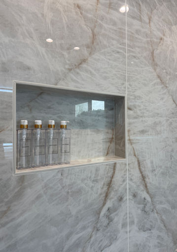 Bottles in shower niche with marble wall for a spa-like experience