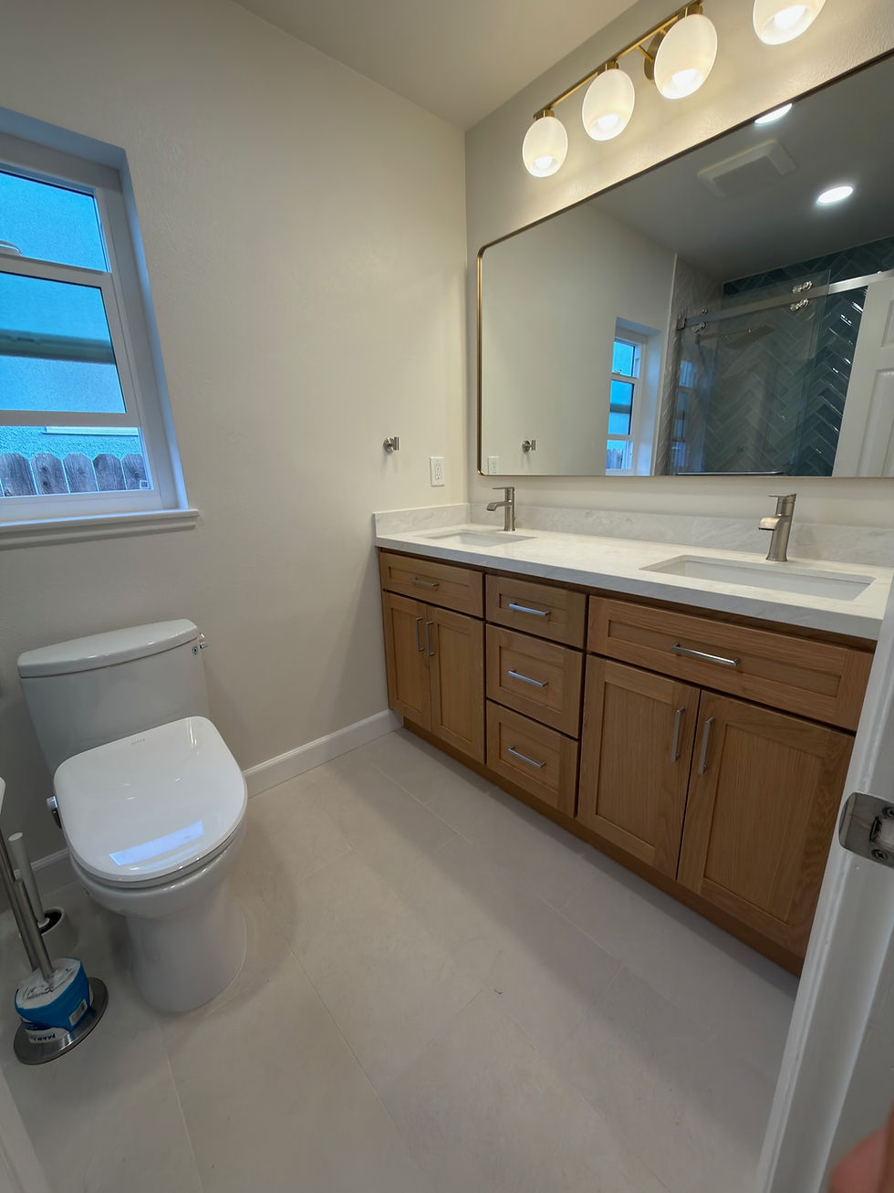 Bathroom renovation with vanity, mirror, toilet, and lighting fixtures; General Contractor OC.