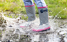 striped rain boots in puddle in grass.jpg
