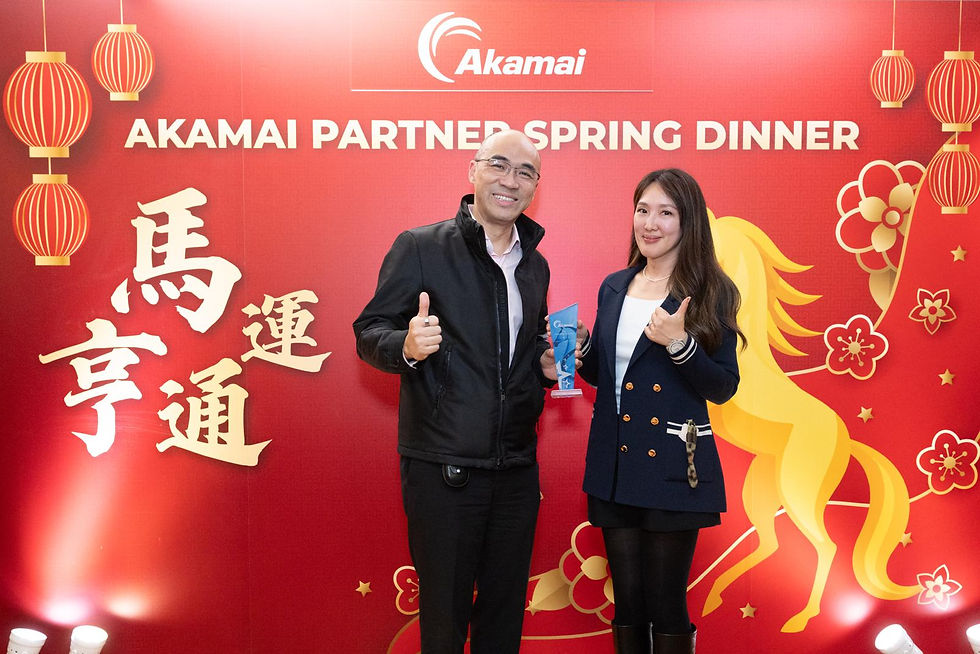 Attendees holding a crystal partner award in front of the red ‘Akamai Partner Spring Dinner’ event backdrop with Akamai logo and festive lantern graphics.