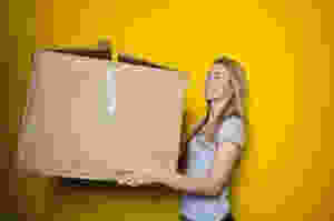 woman in grey shirt holding brown cardboard box