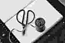 black scissors near thread reel on white book page