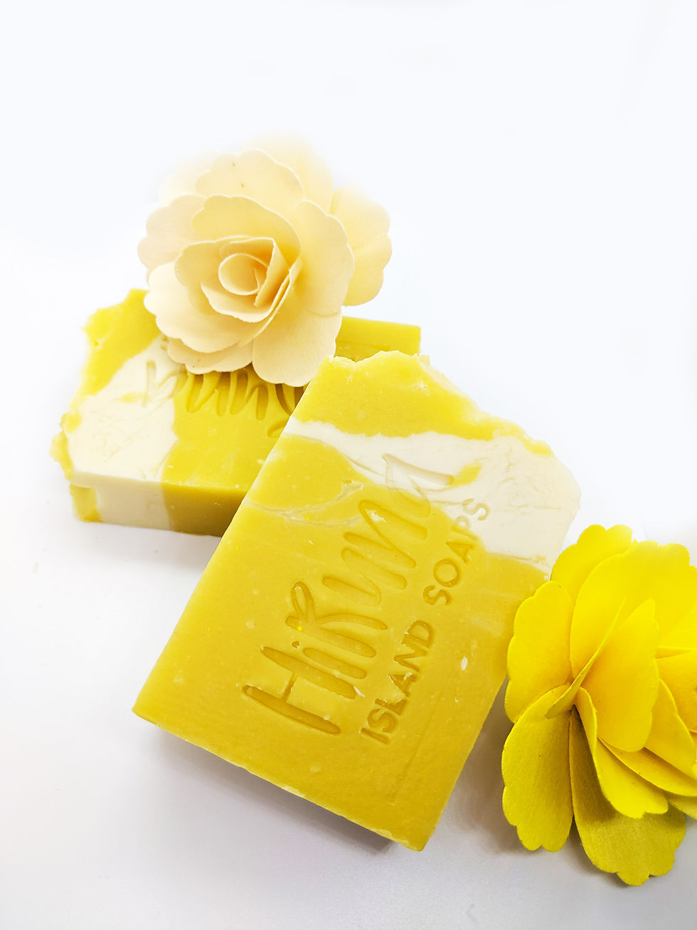 Thumbnail: Two bars of white/yellow bars of soap laying on a white background with a yellow fake flower behind them