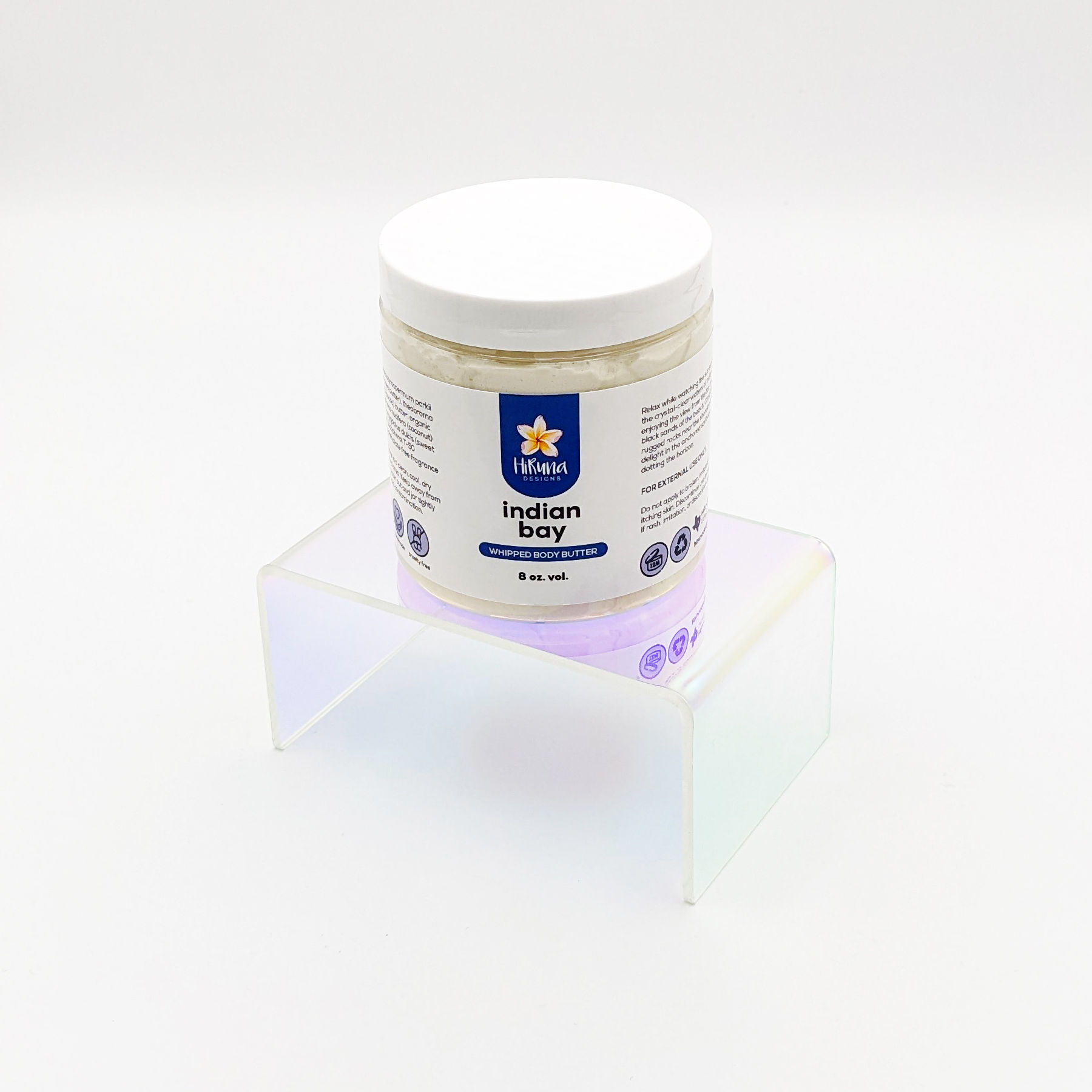 White jar with a white lid and white and blue label sitting on a clear stand on a white background