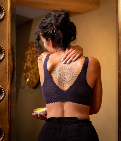 Eine junge Frau salbt sich den Nacken mit Yoga Balsam ein