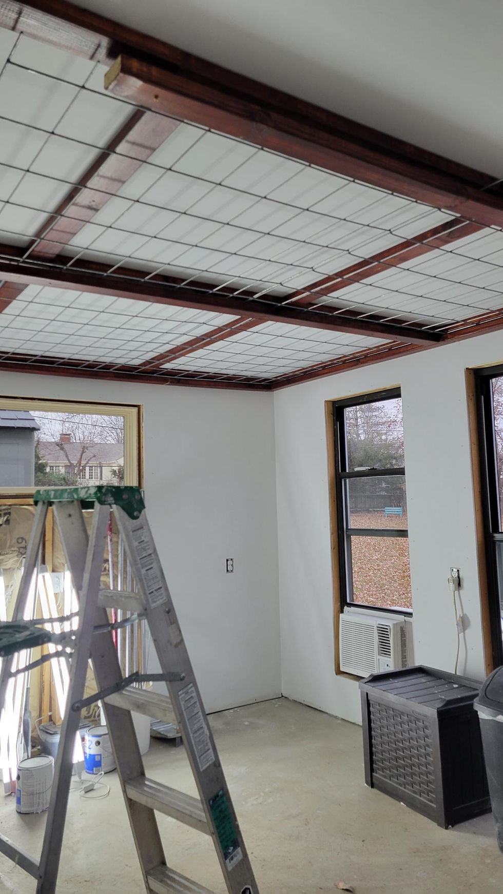 Custom-built plant room ceiling grid made with stained 2x4s and mounted cattle panels, designed for hanging plants in a flexible, moveable arrangement.