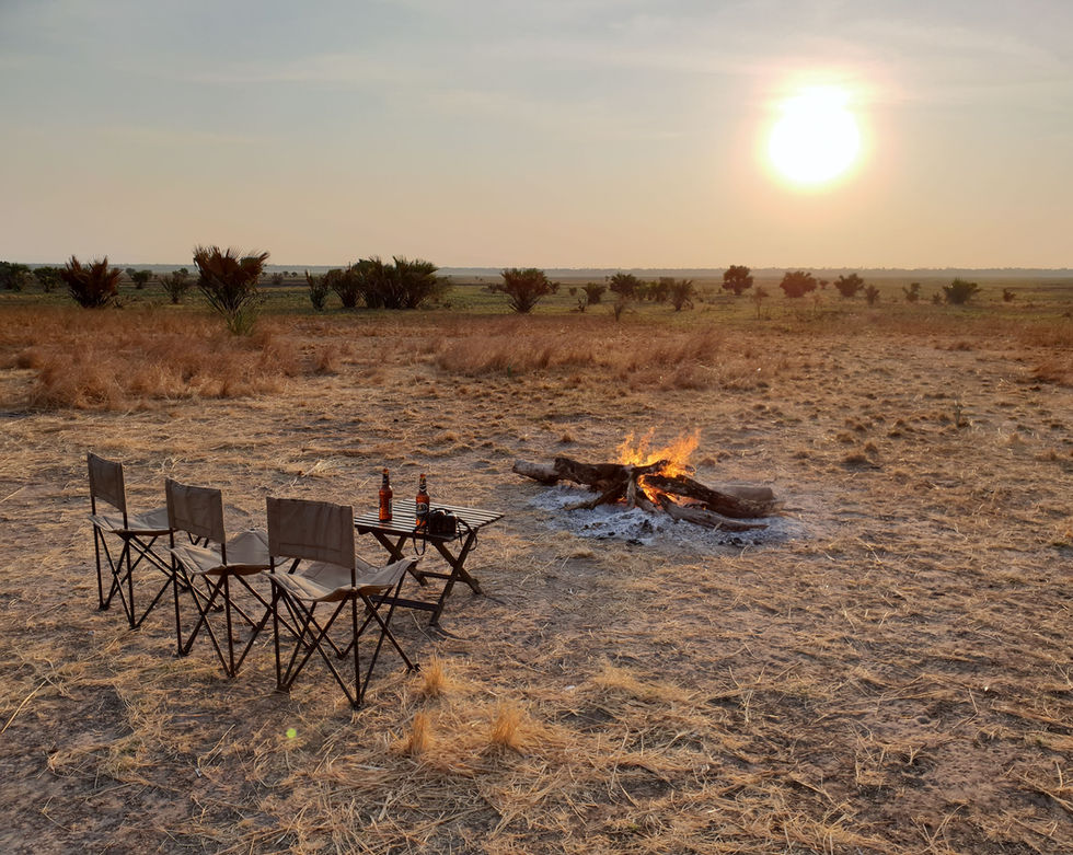 Three chairs face an open fire and the sunset. 