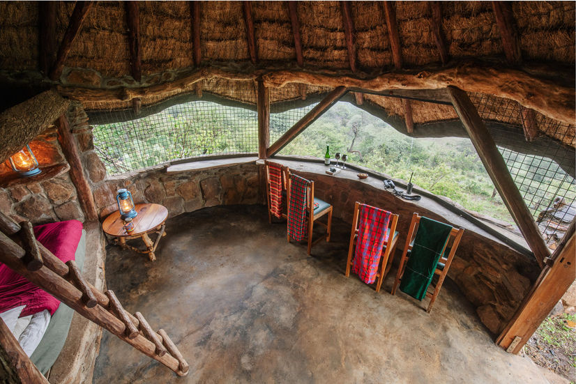A stone chalet has open windows that overlook at waterhole on safari in Kenya with Faran Travel
