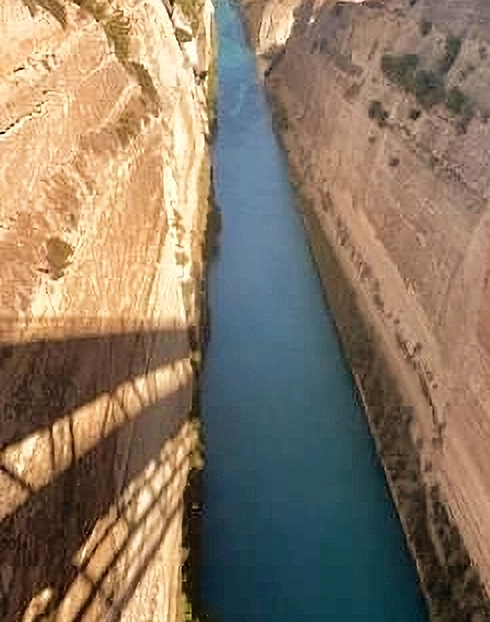 A breathtaking aerial view of the Corinth Canal, a marvel of engineering that slices through the narrow isthmus of Corinth, connecting the Gulf of Corinth with the Saronic Gulf in Greece. The canal's steep limestone walls and striking turquoise waters create a dramatic and awe-inspiring natural and man-made landscape, symbolizing a significant shortcut for ships navigating the region.
