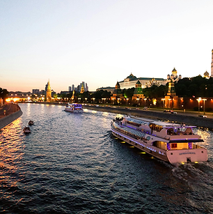 Luxury river cruise boat gliding through a European city at sunset, with historic buildings and warm lights