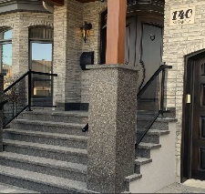 L'entrée d'une maison avec une porte noire élégante et un portail noir coordonné
