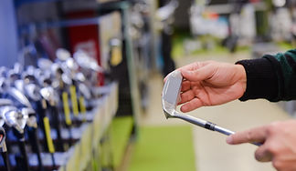 Hand holding a golf stick and stock of golf sticks in front of him