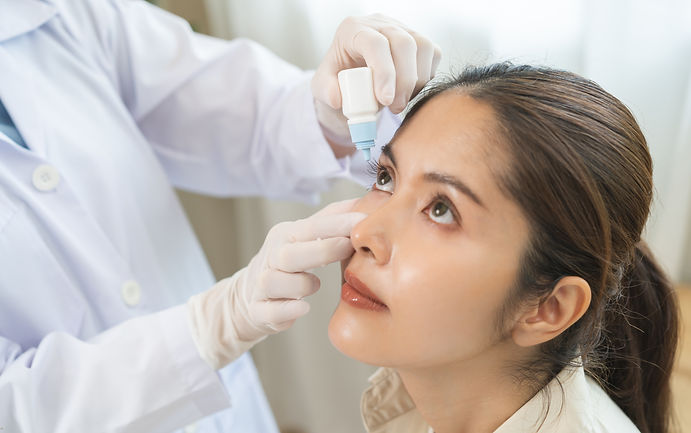 Woman getting eye drops in eyes from doctor