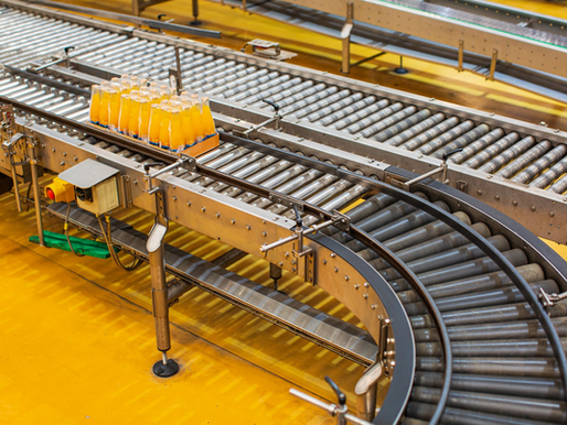 Conveyor belt system in a factory with orange juice bottles in trays