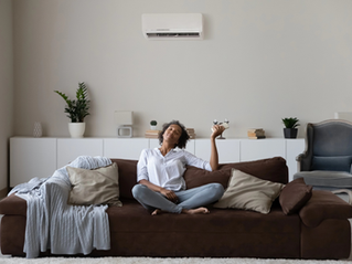 Person relaxing on sofa under a wall-mounted air conditioner in a modern living room