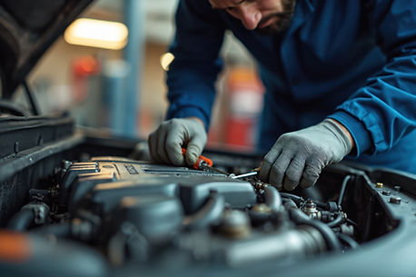 Un mécanicien en salopette bleue et gants travaille avec application sur le moteur d'une voiture dans un garage