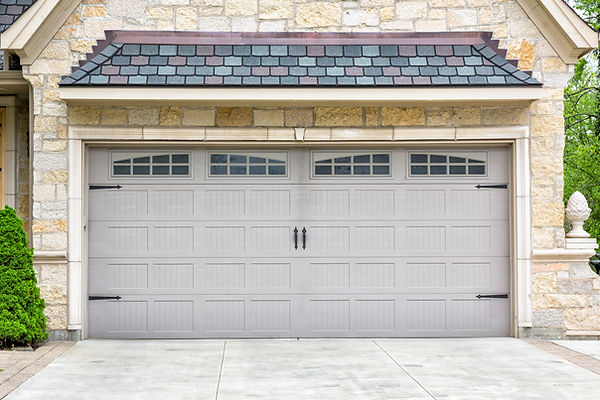 Stone garage with gray double doors featuring small windows