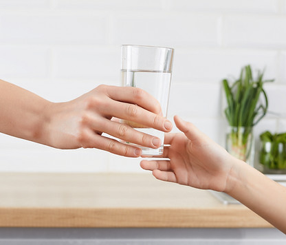 Woman's hand gives a glass of purified water to her child