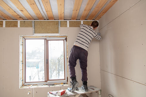 Worker installs drywall on the walls in the room 