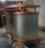 A metallic, rounded industrial structure with orange trim is in a workshop