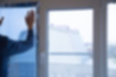 A person applies clear protective film to a large window