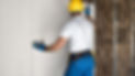 A man wearing a hard hat and blue work gloves installs a wall
