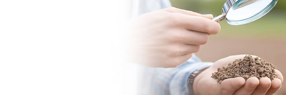 A person examines a heap of soil in their hand using a magnifying glass
