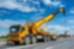 Mobile crane lifting load on highway under blue sky