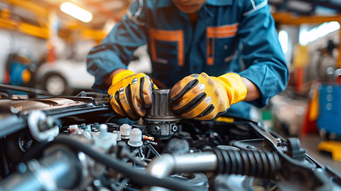 A mechanic wearing orange gloves and a blue uniform works on a car engine in a garage