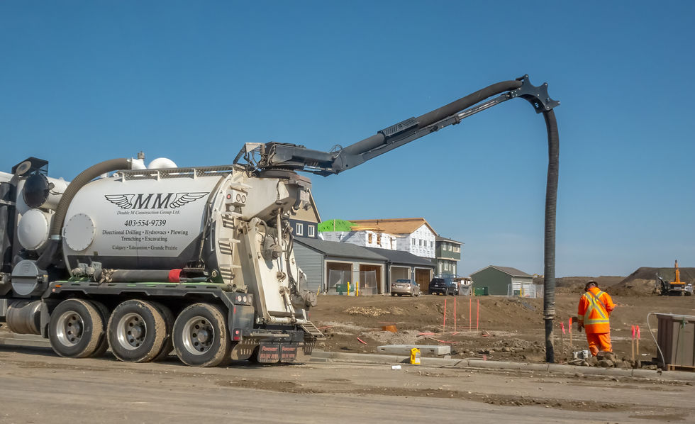 A vacuum truck with a long hose works at a construction site
