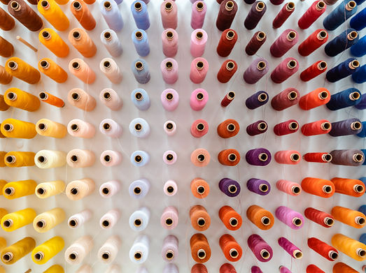 Rows of colorful thread spools arranged diagonally on a wall