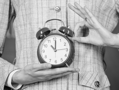 Close-up of person’s hands holding up clock emphasizing the concept of time