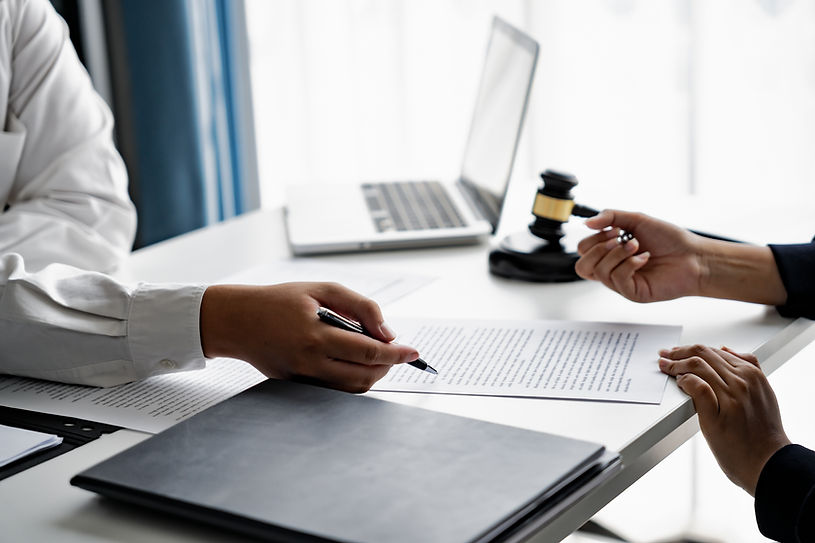 Hands discussing documents at a table with a laptop and gavel nearby