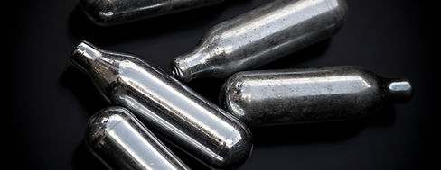 Five shiny, metallic canisters are arranged randomly on a black surface