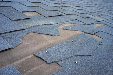 View of shingle roof damage that needs repair after a storm