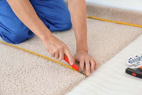 Person cutting beige carpet with a utility knife