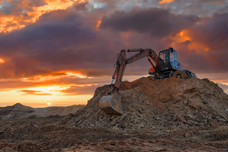 Une excavatrice est posée sur un monticule de terre